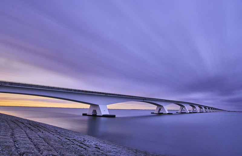Low angle view of bridge over sea against sky. calm. sunset. soft colour. 