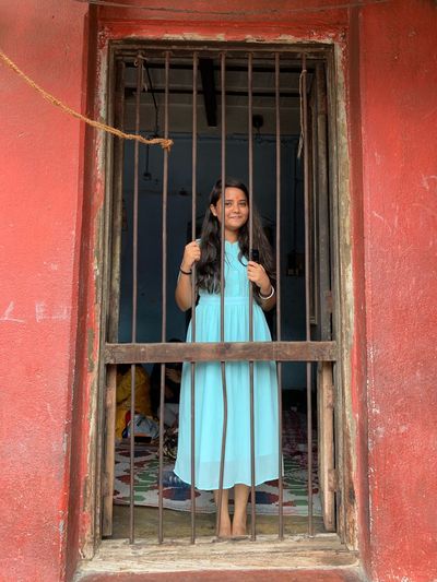 Portrait of smiling girl standing against window
