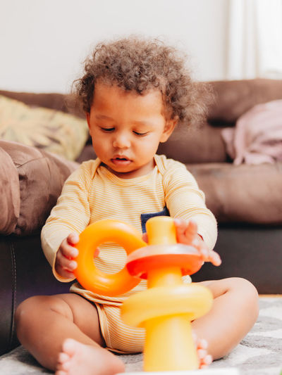 Cute mixed race or biracial baby boy playing with learning toys in the living room at home 