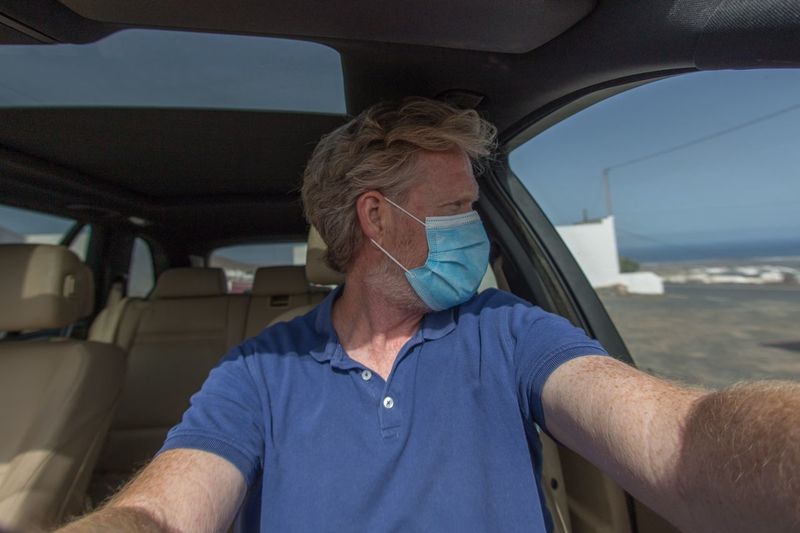 Man wearing mask looking through window in car