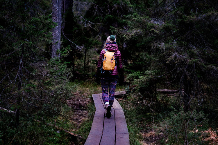 Woman walking along a boardwalk in the forest hiking in winter