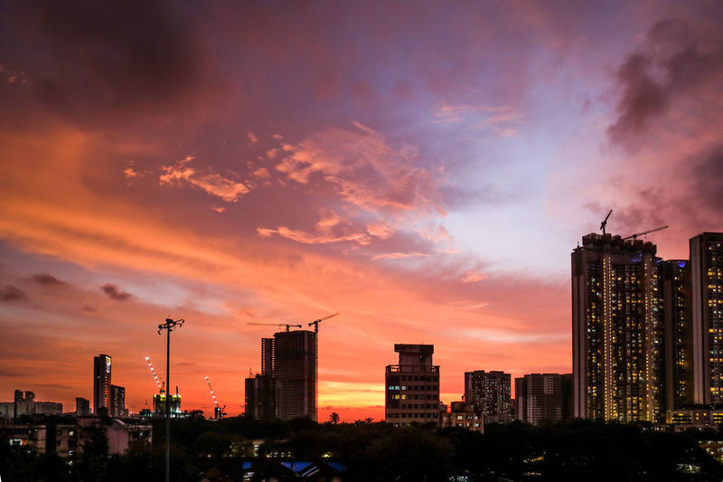 Modern buildings against dramatic sky during sunset
