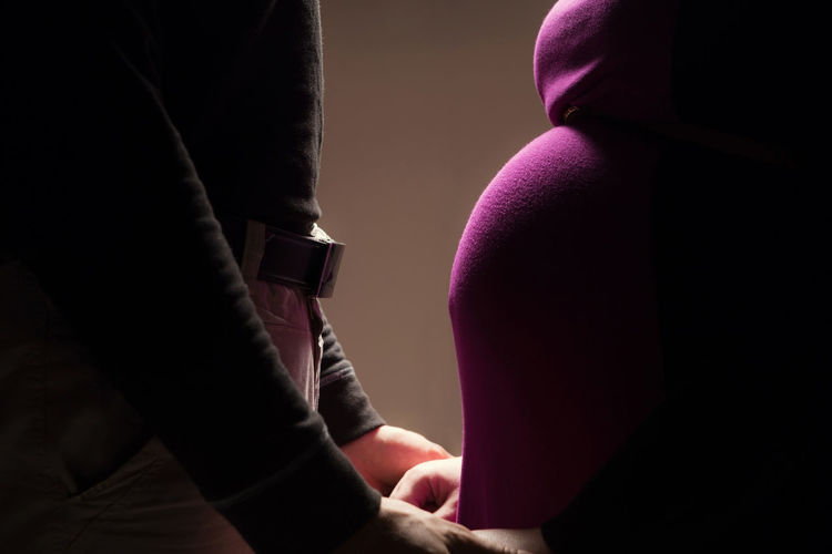 Midsection of pregnant woman standing with man