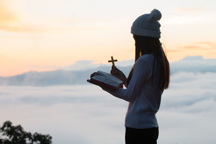 Rear view of woman standing against sky during sunset