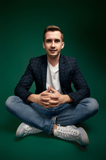 Portrait of young man sitting against black background