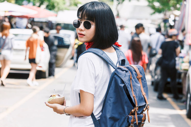 Portrait of young woman having snack on city street in city