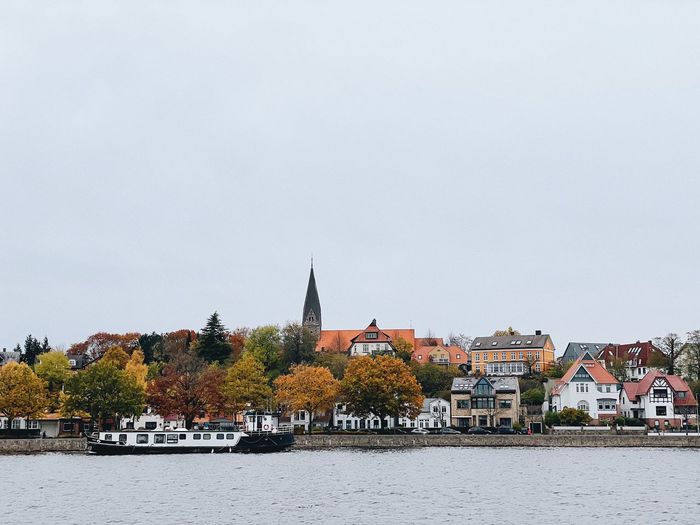 Buildings by river against sky in city