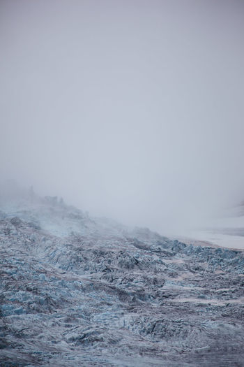 Scenic view on glacier against sky filled with fog
