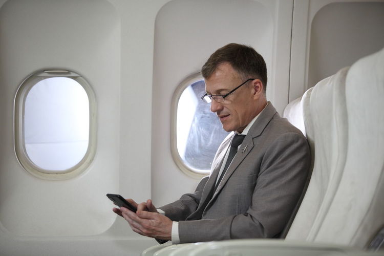 Rear view of man using mobile phone while sitting in airplane