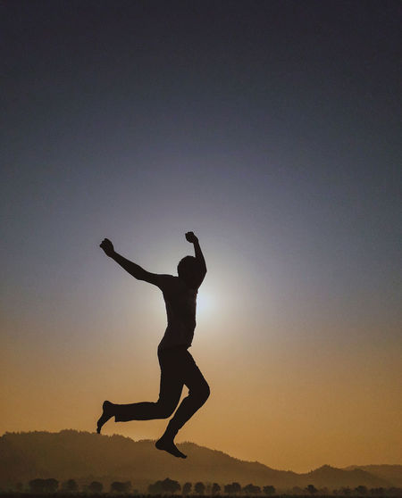 Full length of silhouette man jumping against sky during sunset