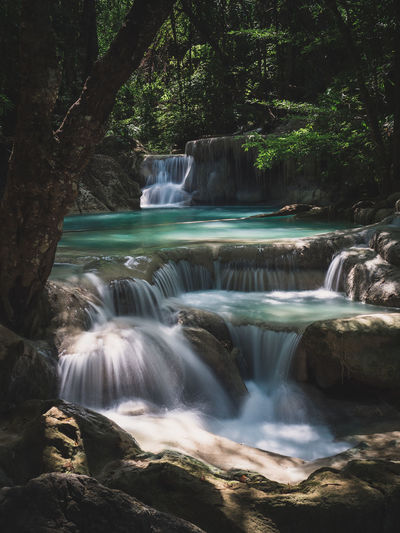Scenic waterfall flowing water, turquoise pond in rainforest. erawan falls, kanchanaburi, thailand.