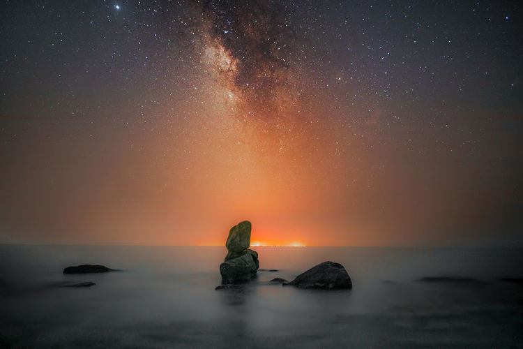 
the lights of lavan island, in the distance of the bay where the galaxy shines above its head
