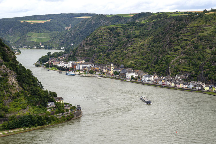 Barge with a covered deck sailing on the river rhine in western germany, visible buildings.