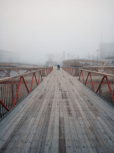 Pier on footbridge against sky during rainy season