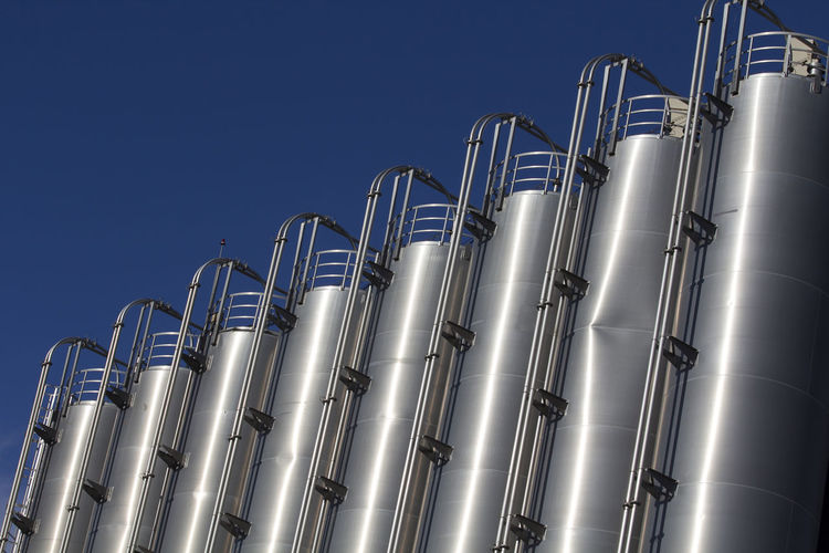 Low angle view of industry against clear blue sky