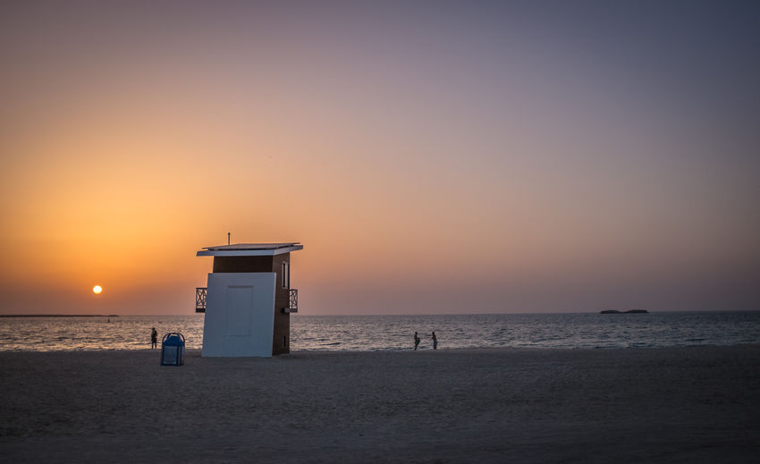 Lifeguard hut at beach against clear sky during sunset