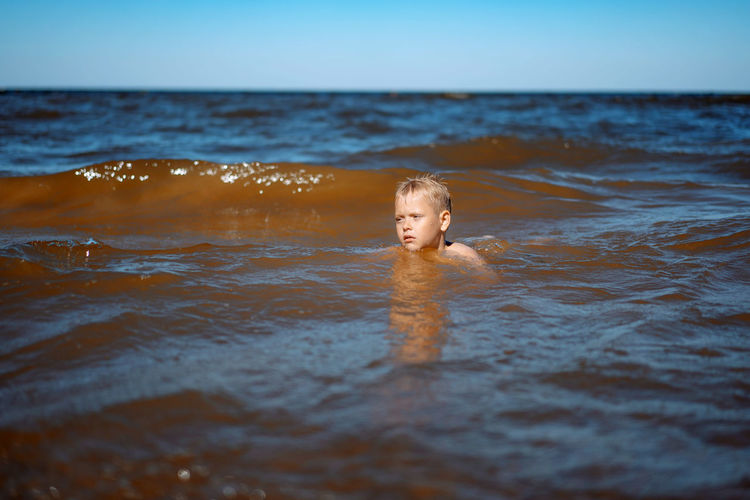7-8 years old cute caucasian boy swimming in the sea