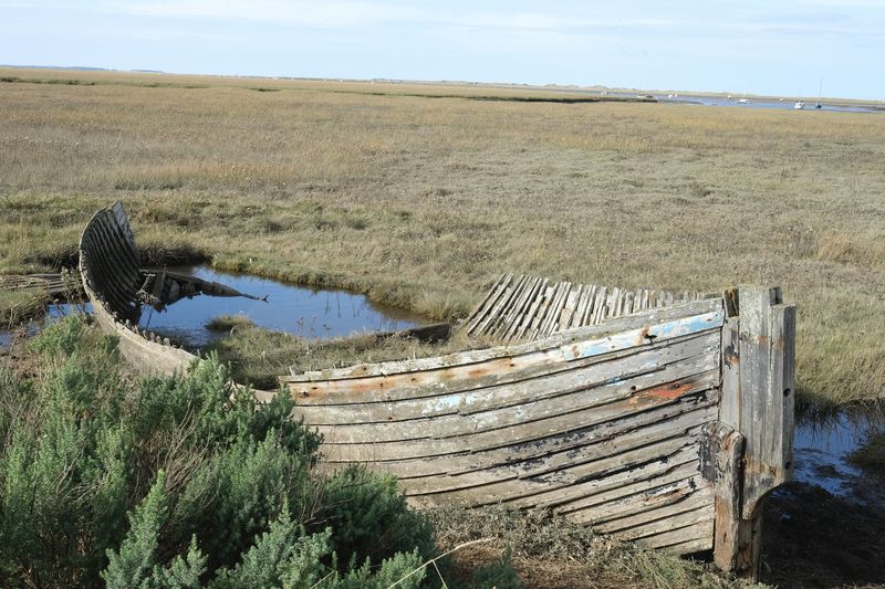 Wooden boat in field against sky