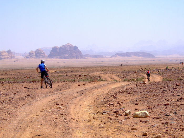 Rear view of men riding bicycle on landscape