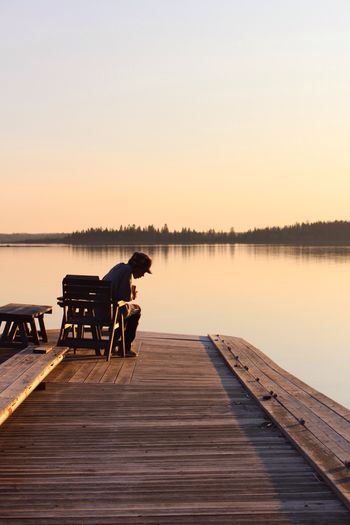 Boy sitting on lakeshore