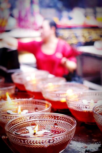 Close up of diyas with woman in background at market