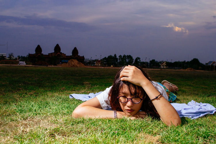 Side view of woman lying on grassy field
