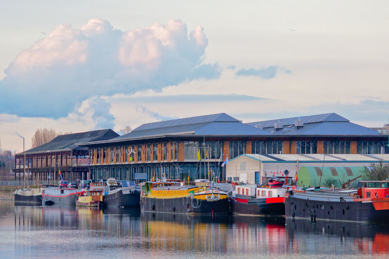 Boats moored at harbor against sky