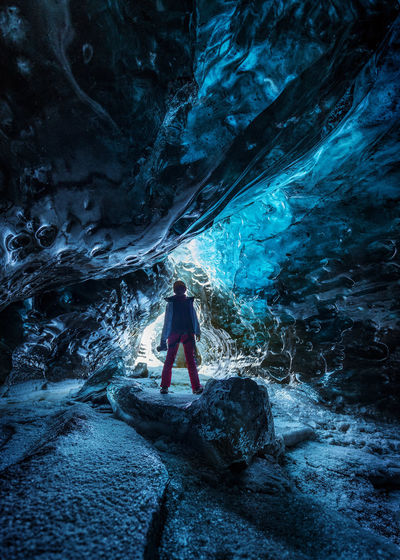Man standing on rock in frozen cave