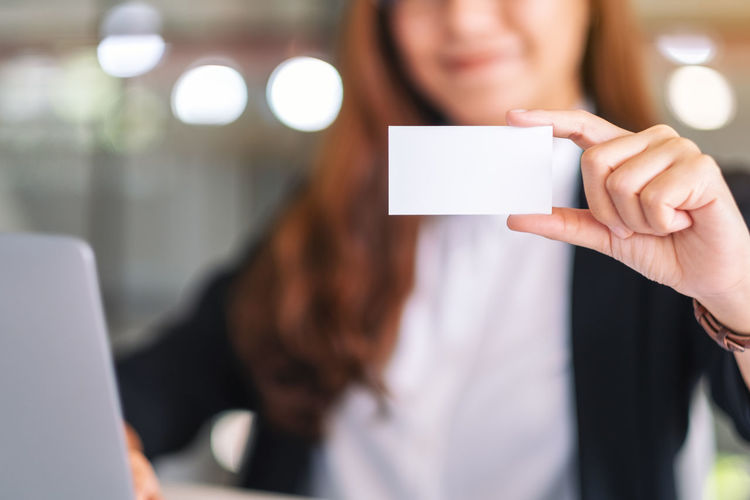 Midsection of businesswoman holding business card in office