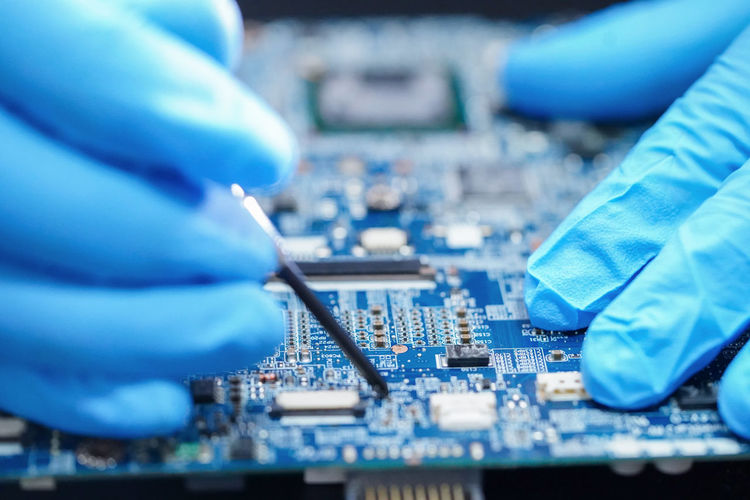 Close-up of hands repairing mother board