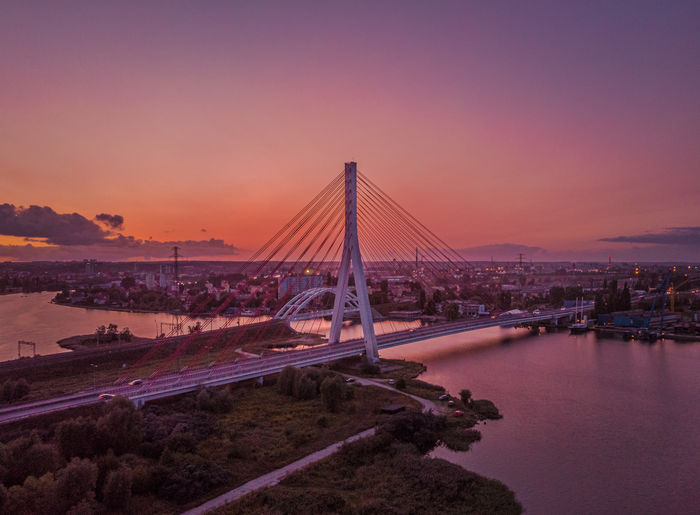Bridge over river in city during sunset