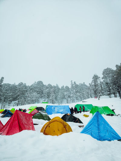 Multi colored tent on snow covered field against sky