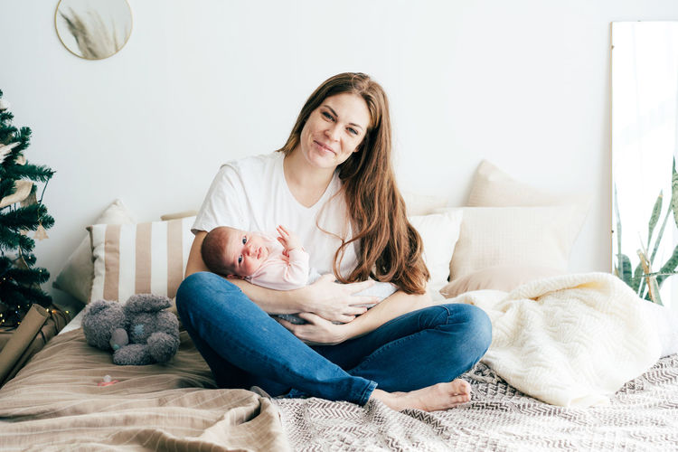 Full length portrait of mother embracing baby at home