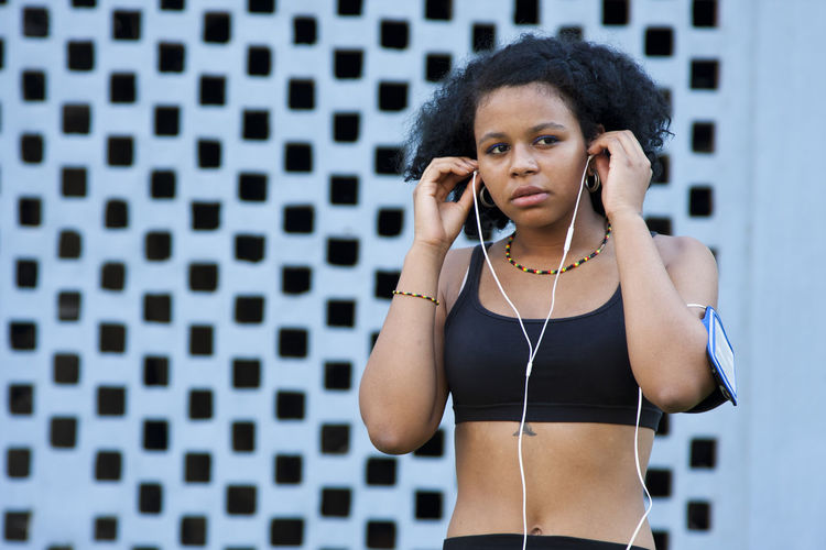 Portrait of young woman standing against wall