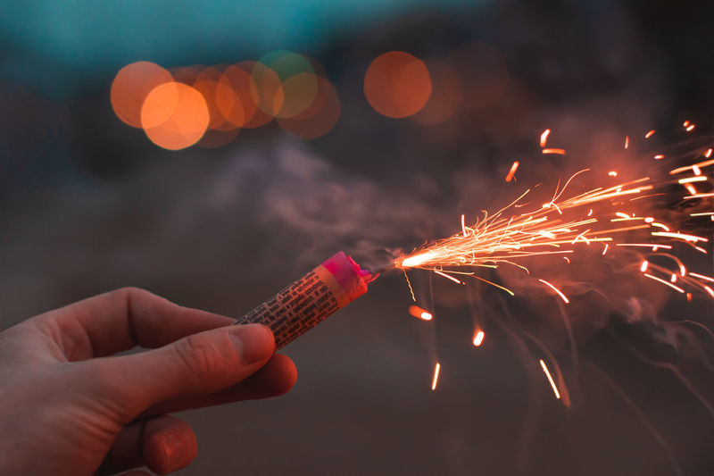 Low angle view of hand holding firework display