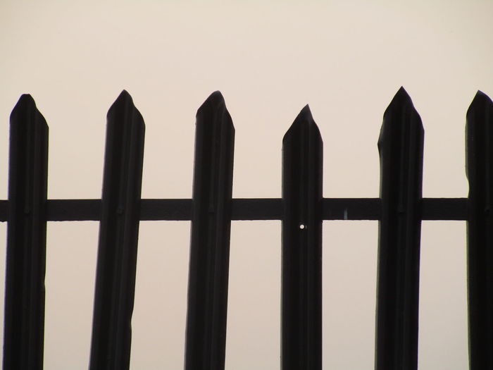 Close-up of silhouette fence against sky during sunset