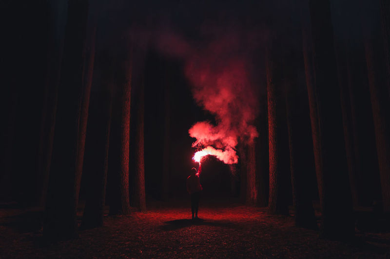 Man standing in illuminated fire at night