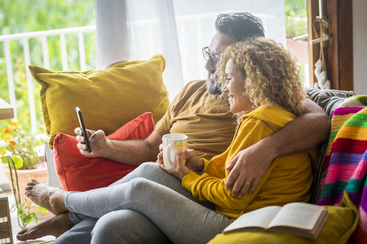 Couple using digital tablet while sitting on sofa at home