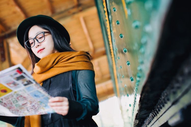 Young woman reading newspaper at railroad station