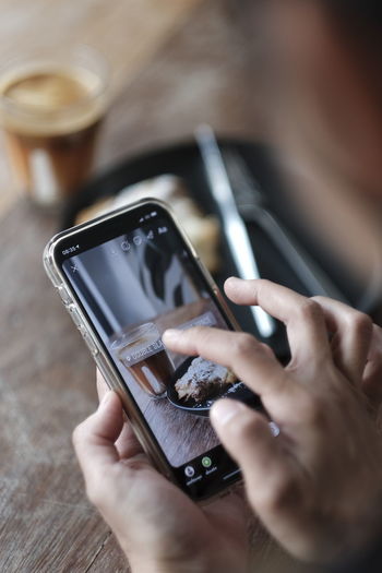Cropped hands of woman clicking pictures of food on table