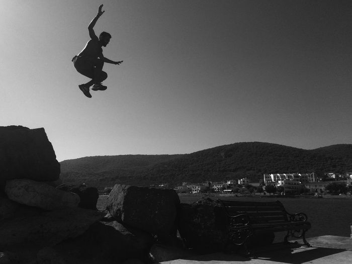 Man in mid-air by sea against clear sky
