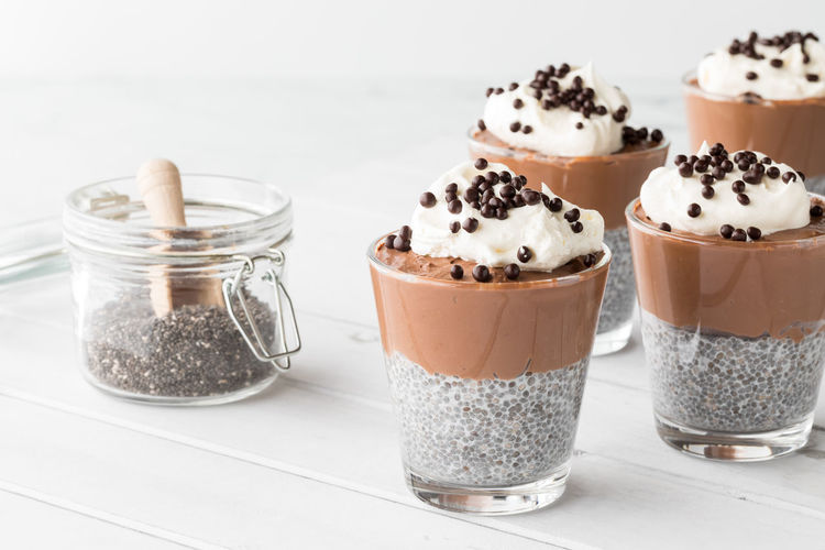 Chocolate mousse chia pudding cups with chia seeds in a jar to the side.